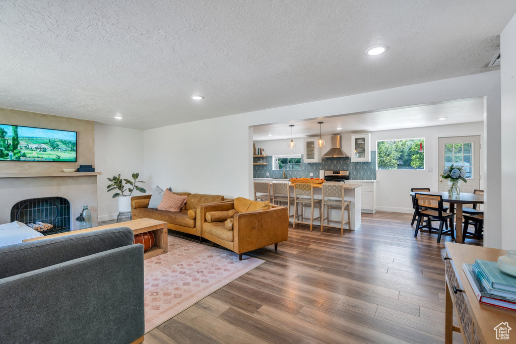 Living room with a textured ceiling, recessed lighting, a large fireplace, and dark wood-type flooring