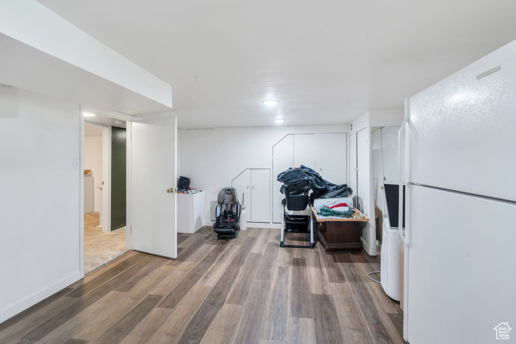 Finished below grade area featuring freestanding refrigerator and wood finished floors