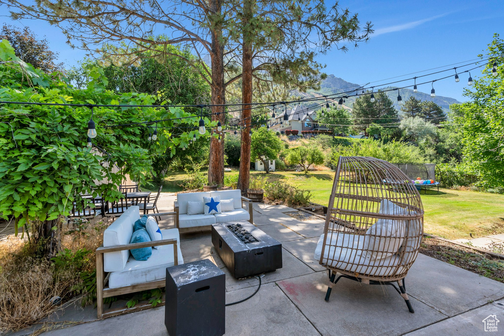 View of patio featuring an outdoor living space with a fire pit, a trampoline, and a mountain view