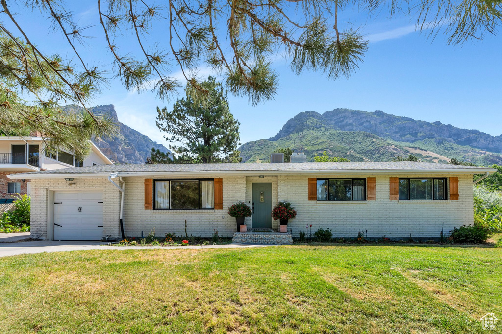 View of front facade featuring a mountain view, a garage, and brick siding