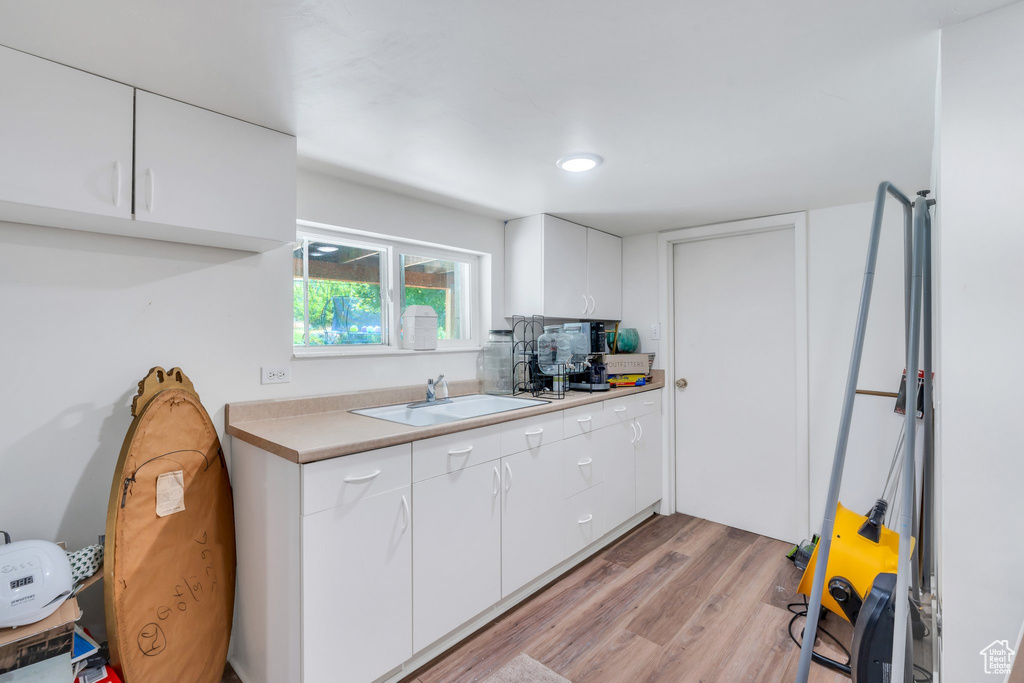 Kitchen featuring light wood-style flooring, light countertops, and white cabinets