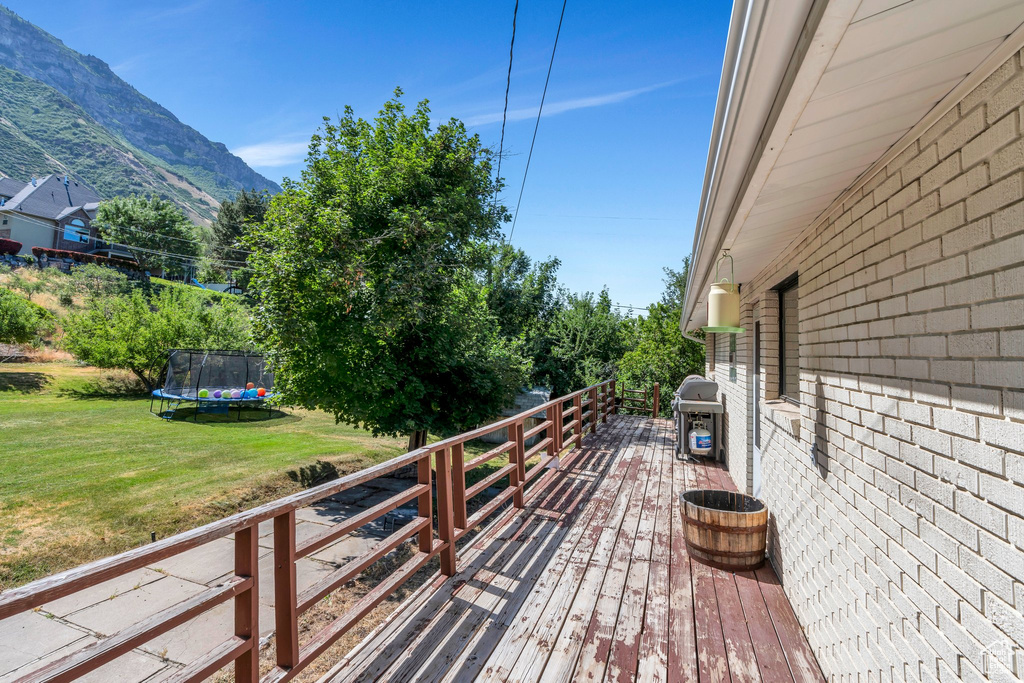 Deck featuring a trampoline, a lawn, area for grilling, and a mountain view