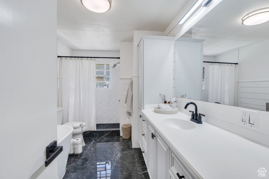 Full bathroom with vanity, tiled shower, and marble finish floors