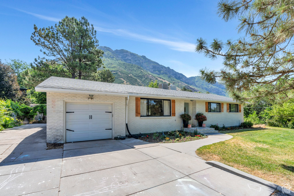 Ranch-style home with a mountain view, a garage, brick siding, and concrete driveway