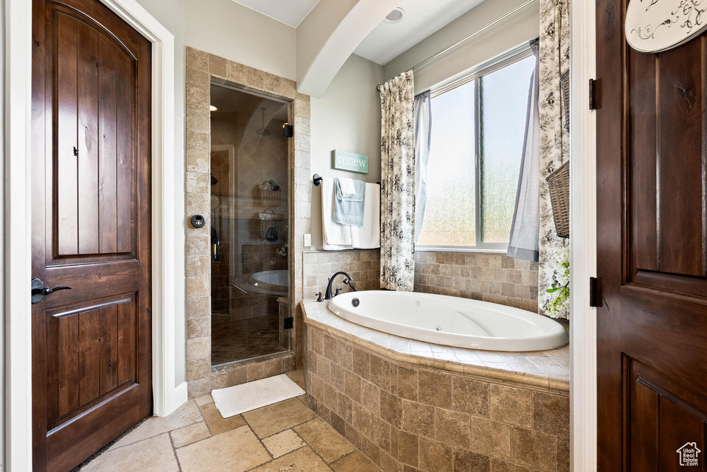 Full bathroom featuring a whirlpool tub, a shower stall, and stone tile flooring