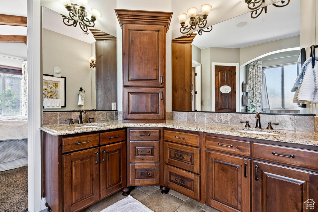 Ensuite bathroom with healthy amount of natural light, double vanity, and a chandelier