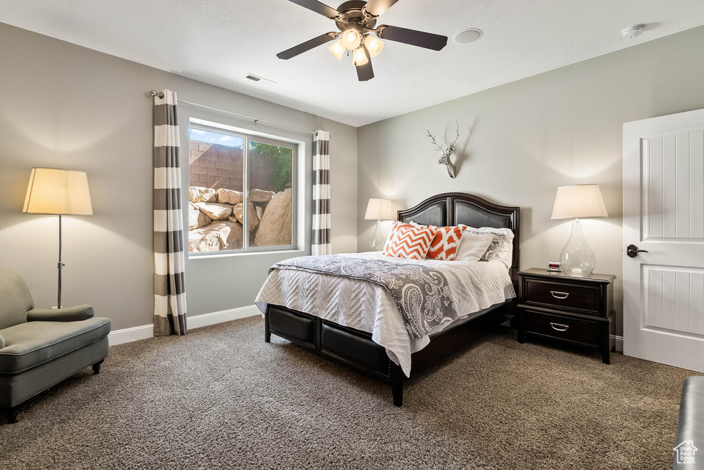 Carpeted bedroom featuring a ceiling fan and baseboards