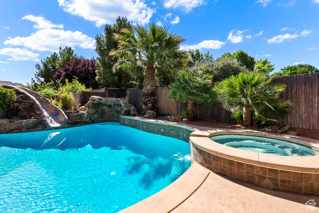 View of pool featuring a fenced backyard and an in-ground hot tub
