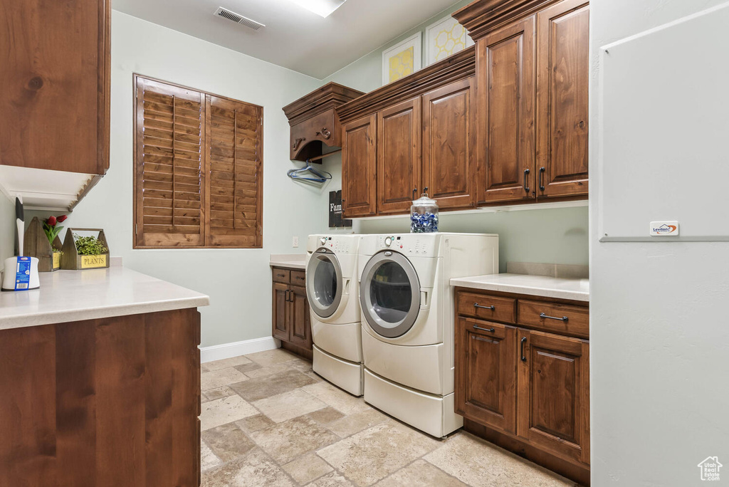 Laundry area with cabinet space, separate washer and dryer, and stone tile flooring