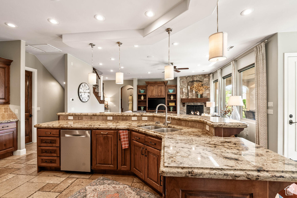 Kitchen with recessed lighting, open floor plan, ceiling fan, a stone fireplace, and light stone countertops