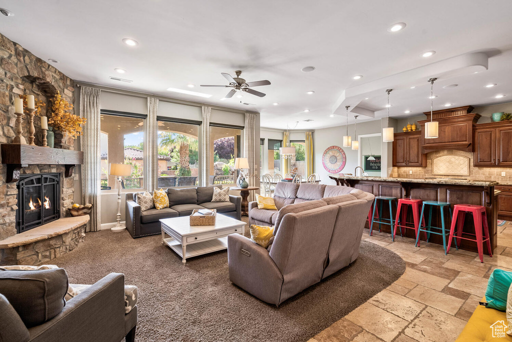 Living area with recessed lighting, ceiling fan, a stone fireplace, and stone tile floors