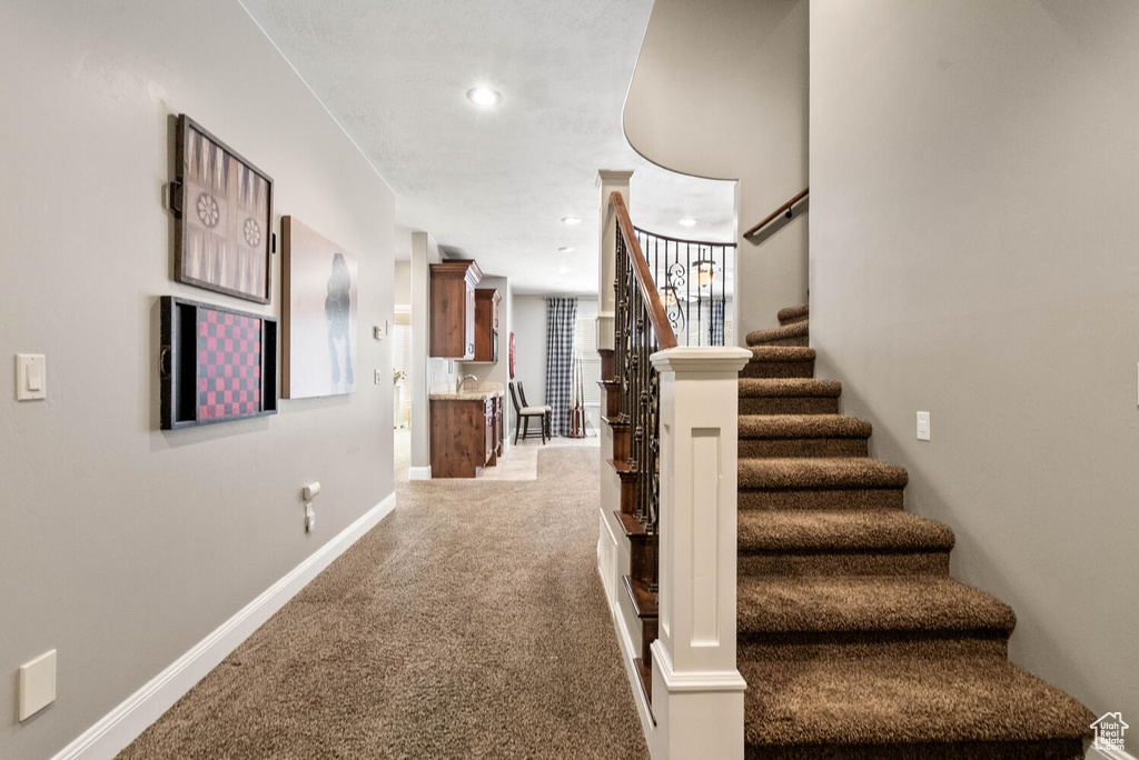 Stairs with carpet flooring and recessed lighting