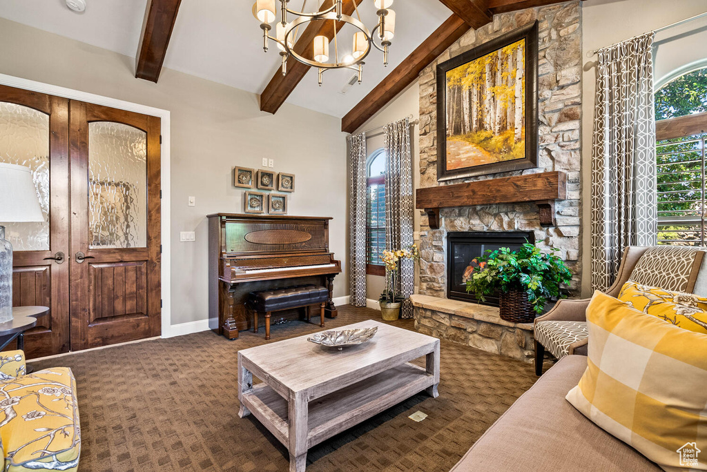 Living area featuring a stone fireplace, a chandelier, and dark carpet