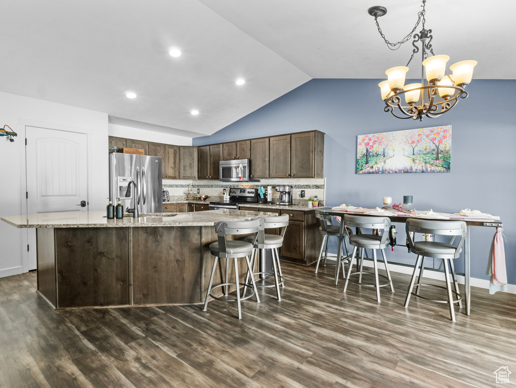 Kitchen with stainless steel appliances, tasteful backsplash, lofted ceiling, dark wood-type flooring, and a chandelier