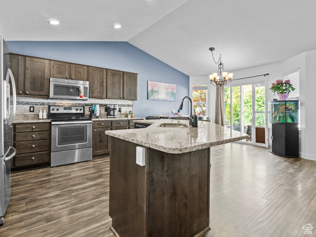 Kitchen featuring stainless steel appliances, lofted ceiling, dark wood-style flooring, decorative backsplash, and dark brown cabinetry
