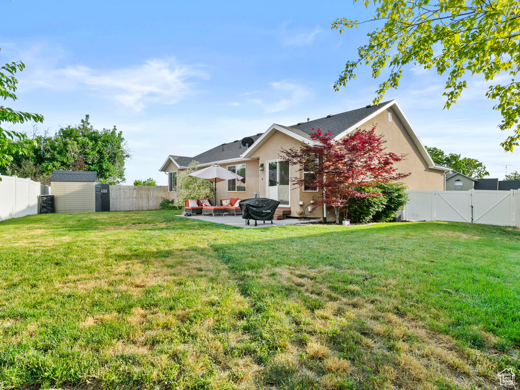 Fenced backyard featuring a gate, a patio, a shed, and an outdoor living space