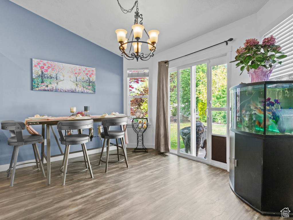 Dining room featuring a chandelier, wood finished floors, and lofted ceiling
