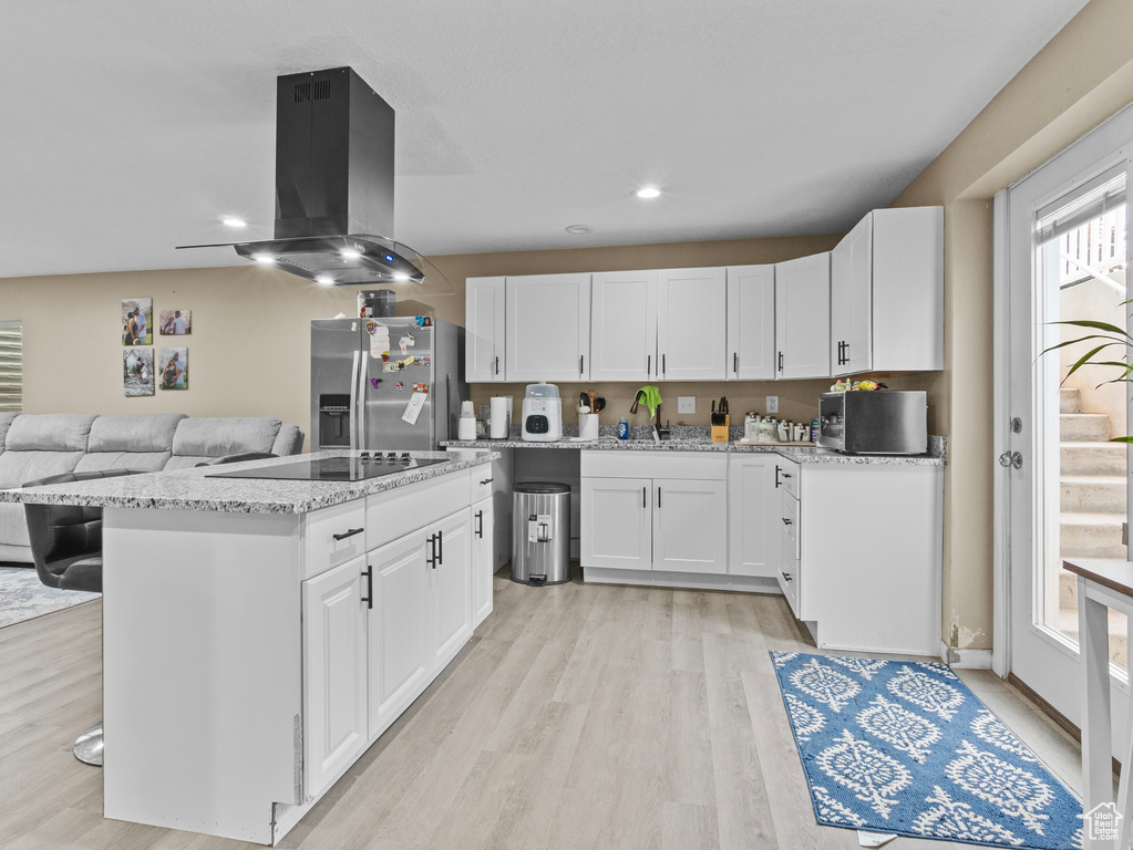Kitchen with stainless steel fridge with ice dispenser, black electric stovetop, island range hood, light wood-style flooring, and recessed lighting