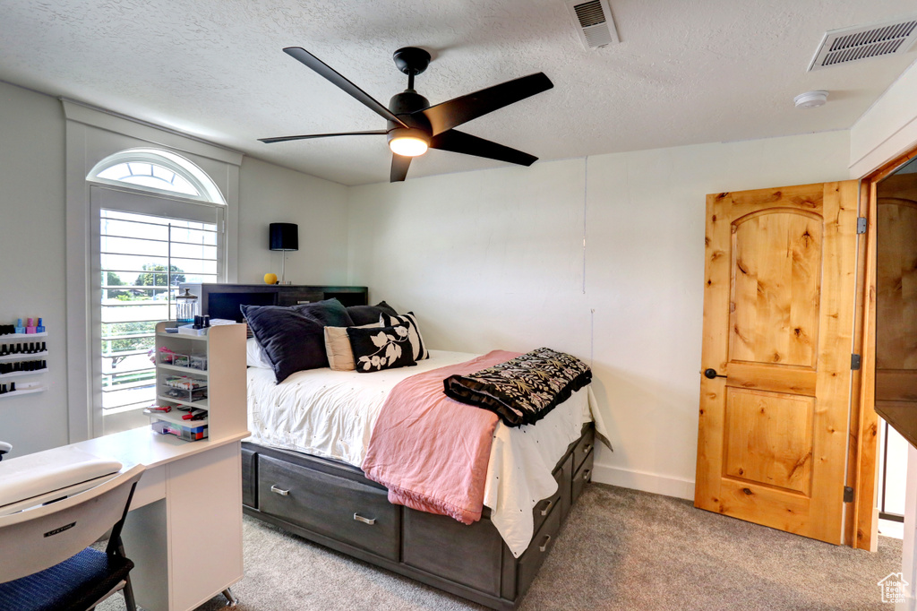 Bedroom featuring light carpet, a textured ceiling, a ceiling fan, and an office area