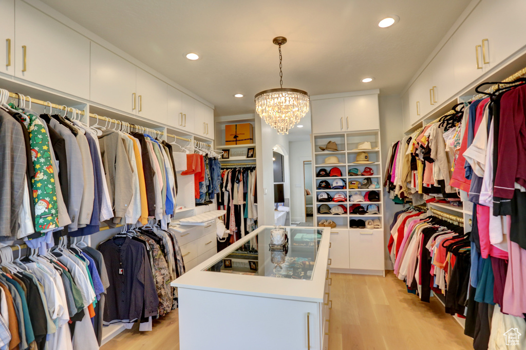 Spacious closet with arched walkways, light wood finished floors, and a chandelier