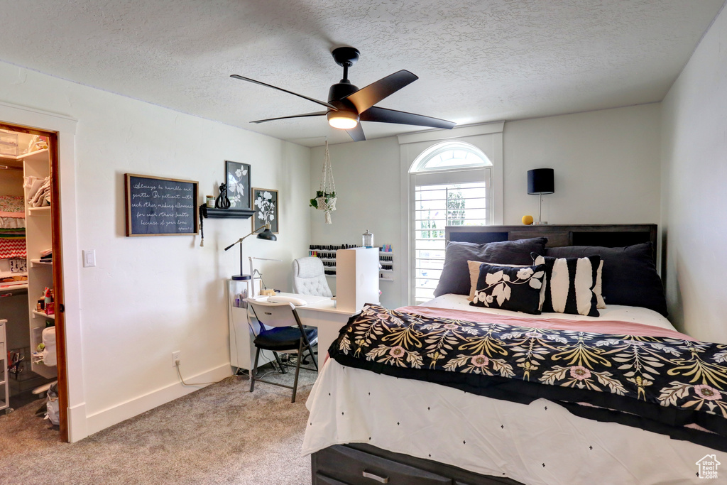 Bedroom featuring carpet, a spacious closet, a textured ceiling, and ceiling fan