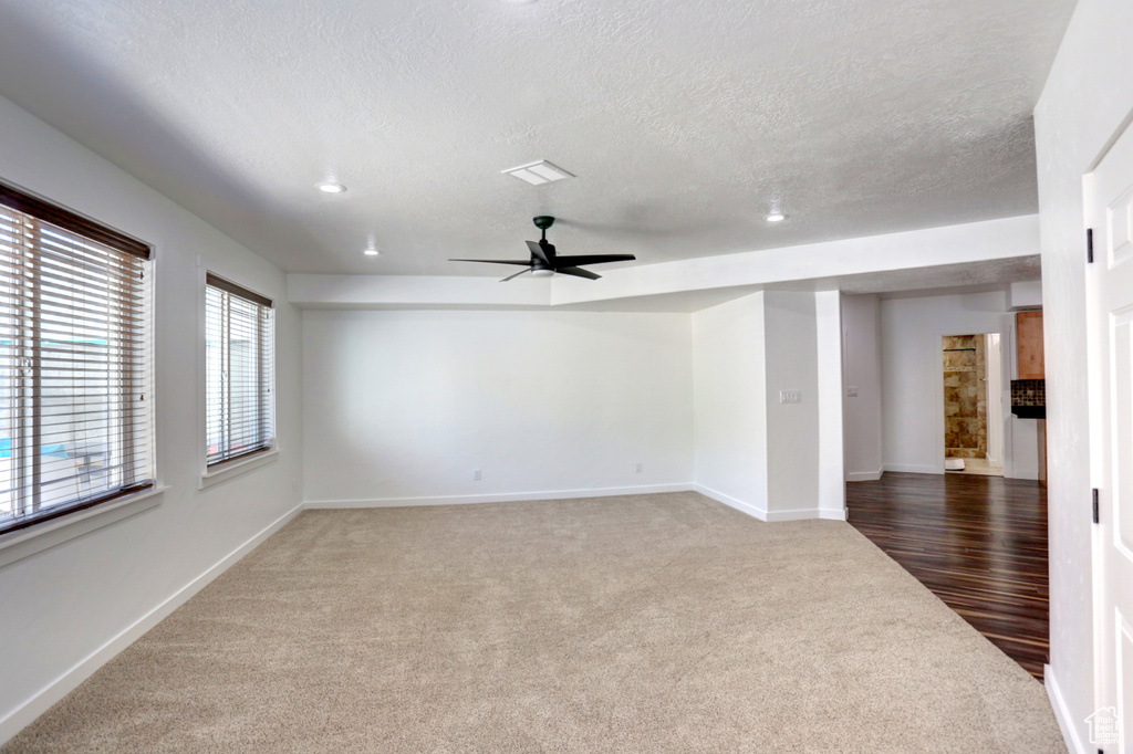 Carpeted empty room featuring ceiling fan and a textured ceiling