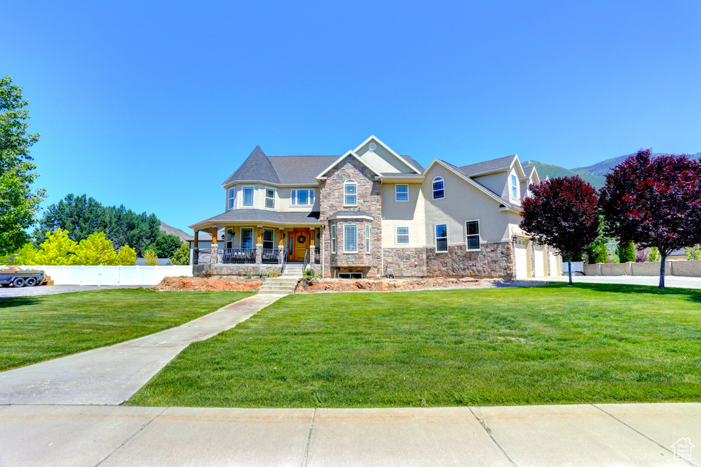 View of front of house featuring stone siding, a porch, and stucco siding
