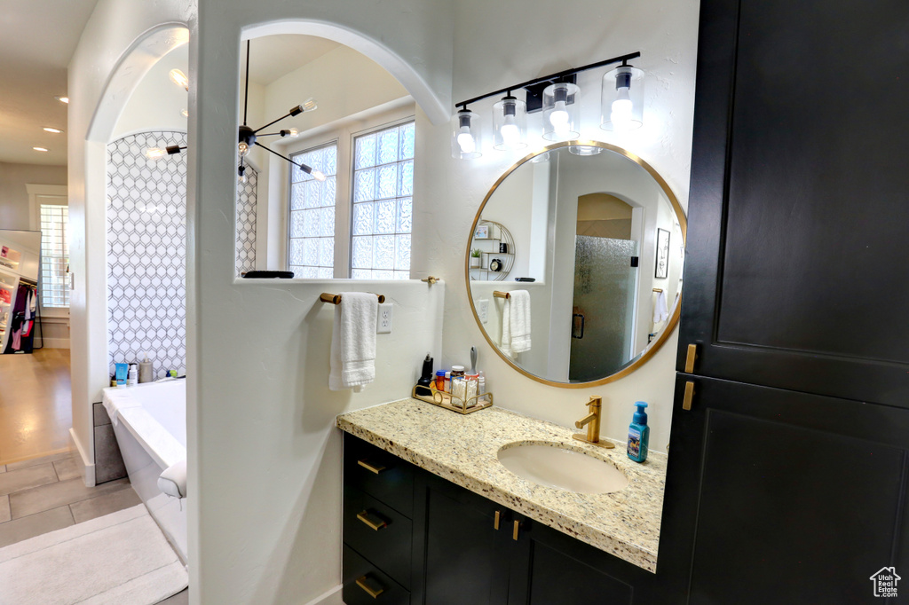 Bathroom with a tub, vanity, a shower, and recessed lighting