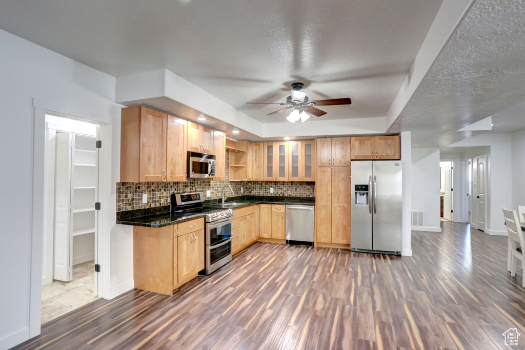 Kitchen with stainless steel appliances, dark wood finished floors, a ceiling fan, decorative backsplash, and light brown cabinetry