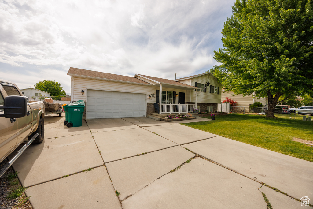 Split level home with an attached garage, concrete driveway, and covered porch