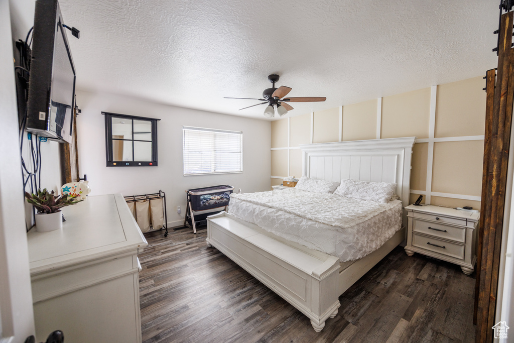 Bedroom with dark wood finished floors, a textured ceiling, and ceiling fan