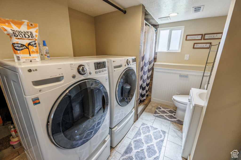 Laundry room featuring independent washer and dryer, a wainscoted wall, and a textured ceiling