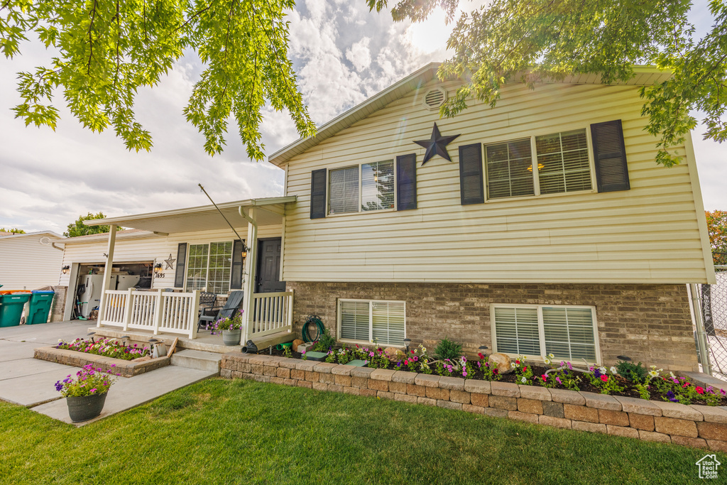 Tri-level home featuring a front yard, driveway, brick siding, and a garage