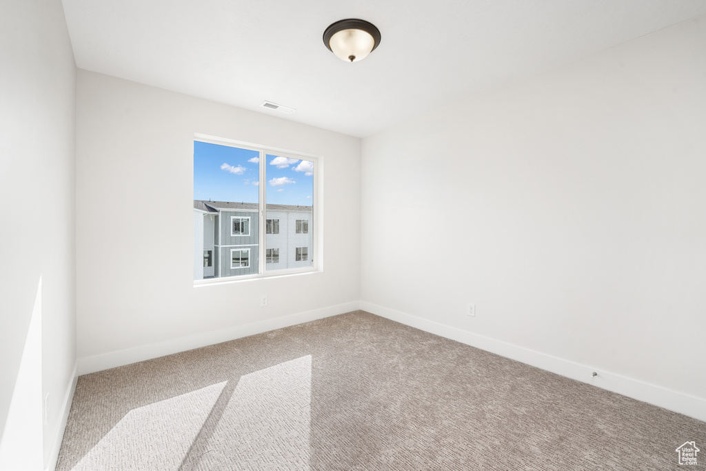Carpeted spare room featuring baseboards