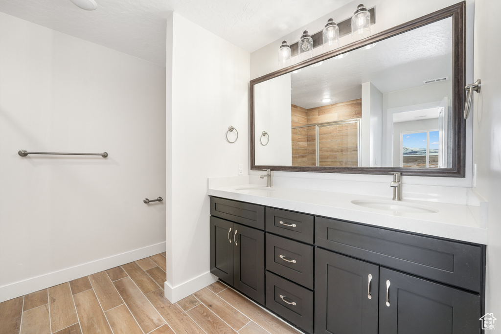 Full bath featuring double vanity, a shower stall, and wood finished floors