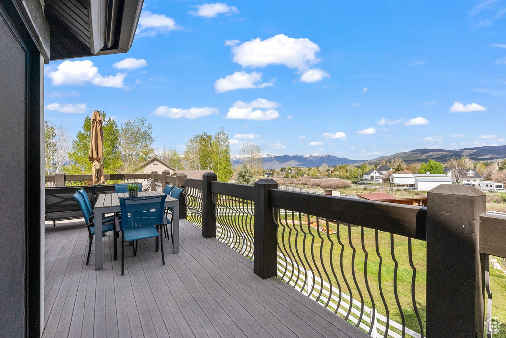 Deck with a mountain view, outdoor dining area, and a lawn