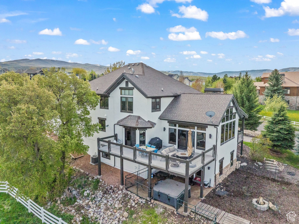 Back of house featuring roof with shingles, stucco siding, an outdoor living space with a fire pit, and a deck with mountain view