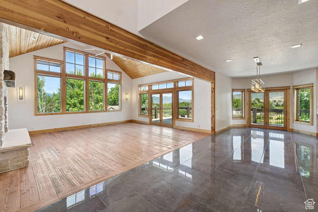 Unfurnished living room featuring plenty of natural light, french doors, and high vaulted ceiling