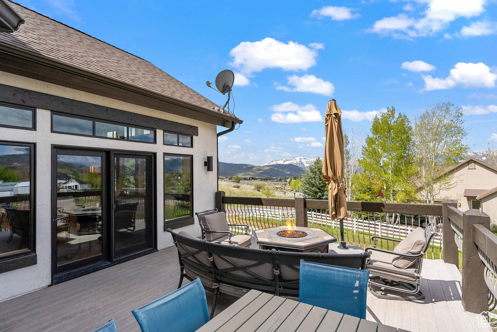 Wooden deck with an outdoor fire pit and a mountain view