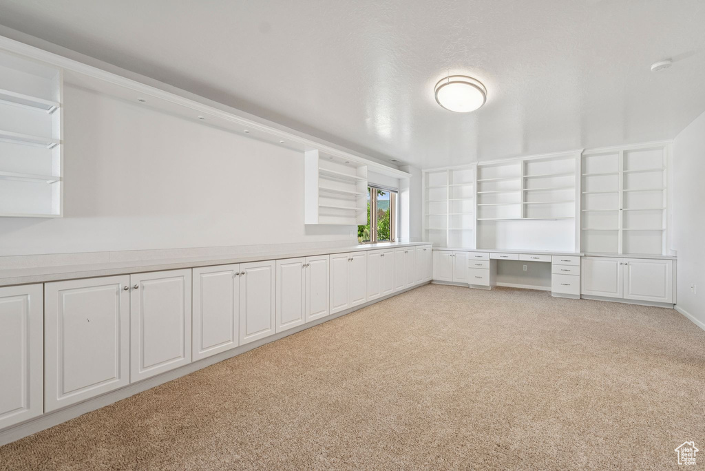 Unfurnished room with light colored carpet, a smoke detector, and built in study area