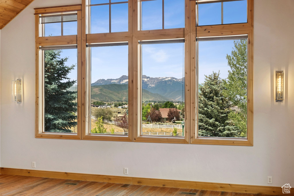 Spare room with a mountain view, wood finished floors, and vaulted ceiling