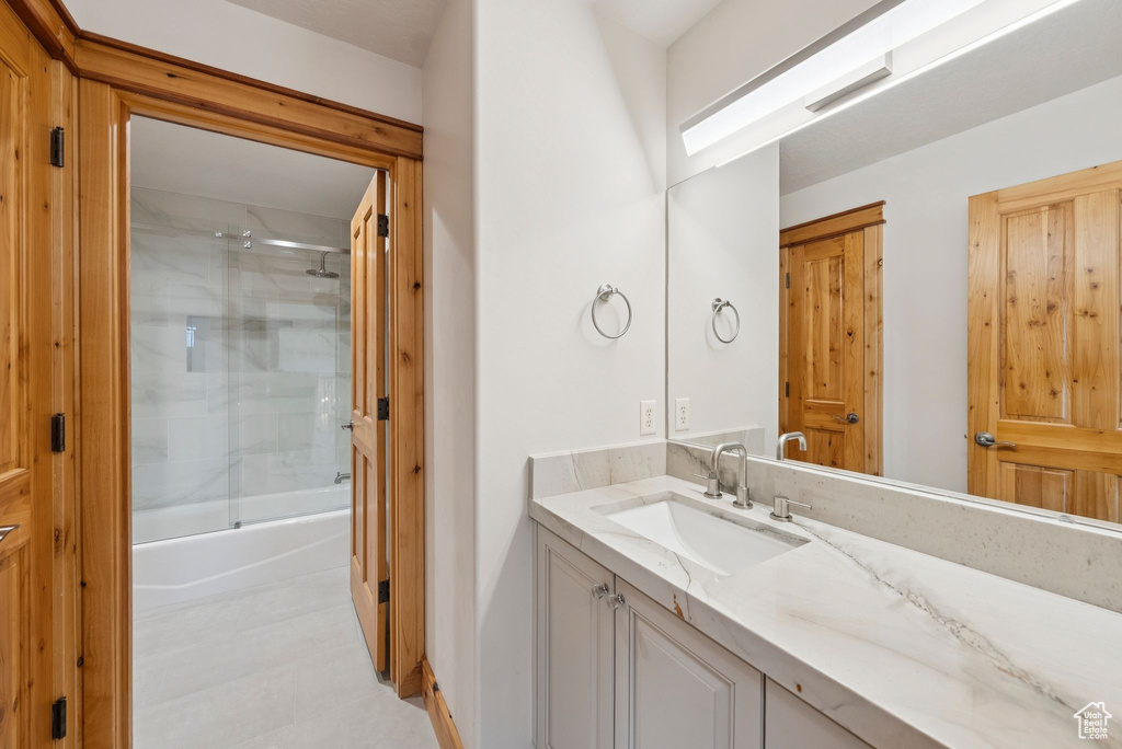 Bathroom featuring vanity and combined bath / shower with glass door