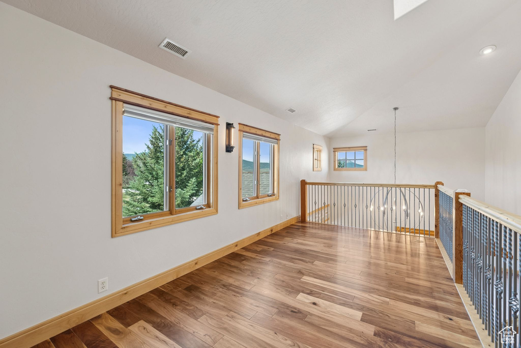 Spare room with wood finished floors, lofted ceiling, and recessed lighting