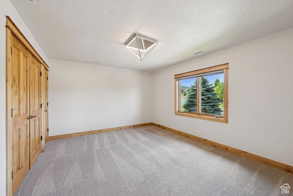 Unfurnished bedroom featuring light carpet and a textured ceiling