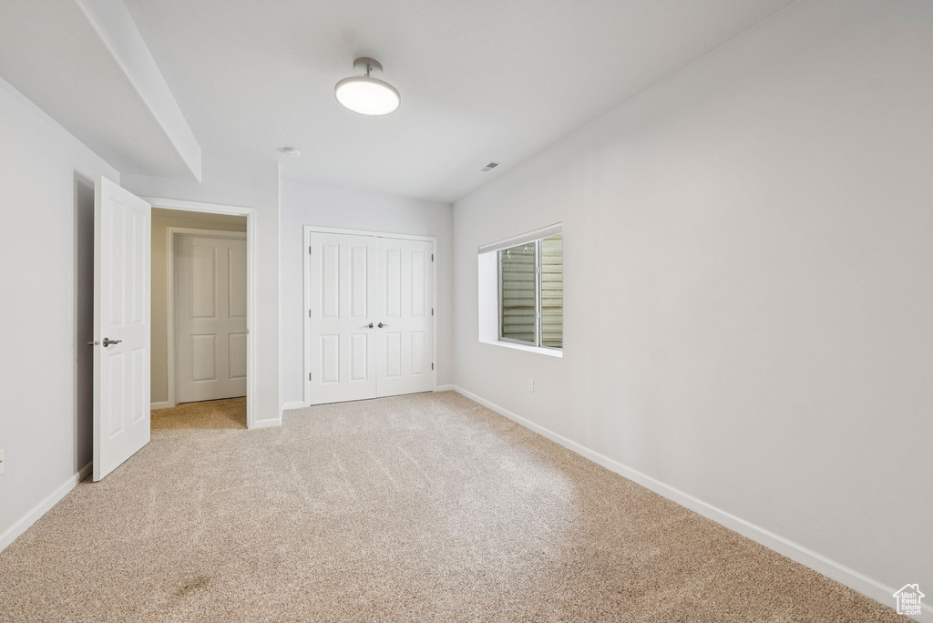 Unfurnished bedroom featuring light carpet and a closet