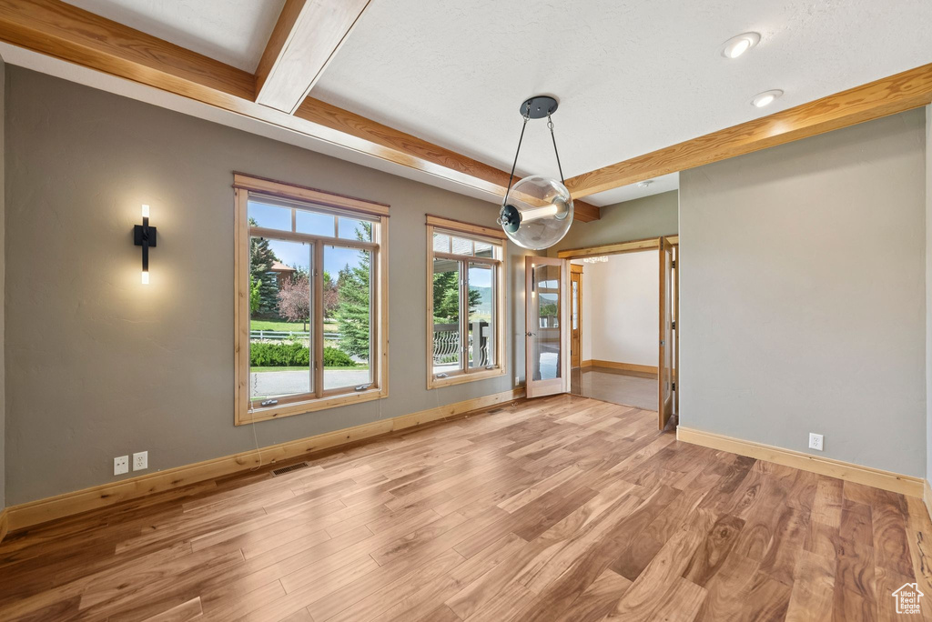Unfurnished dining area with wood finished floors and beamed ceiling