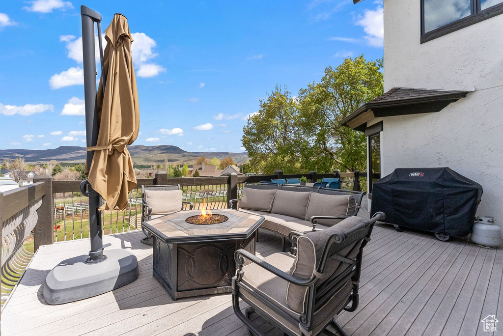 Deck with grilling area, an outdoor living space with a fire pit, and a mountain view
