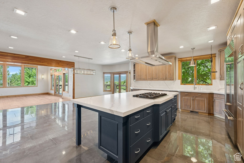 Kitchen featuring island range hood, a textured ceiling, stainless steel gas stovetop, light countertops, and recessed lighting