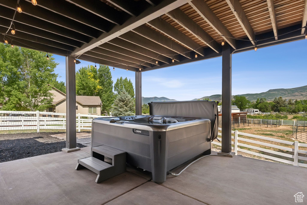 View of patio with a mountain view and a hot tub