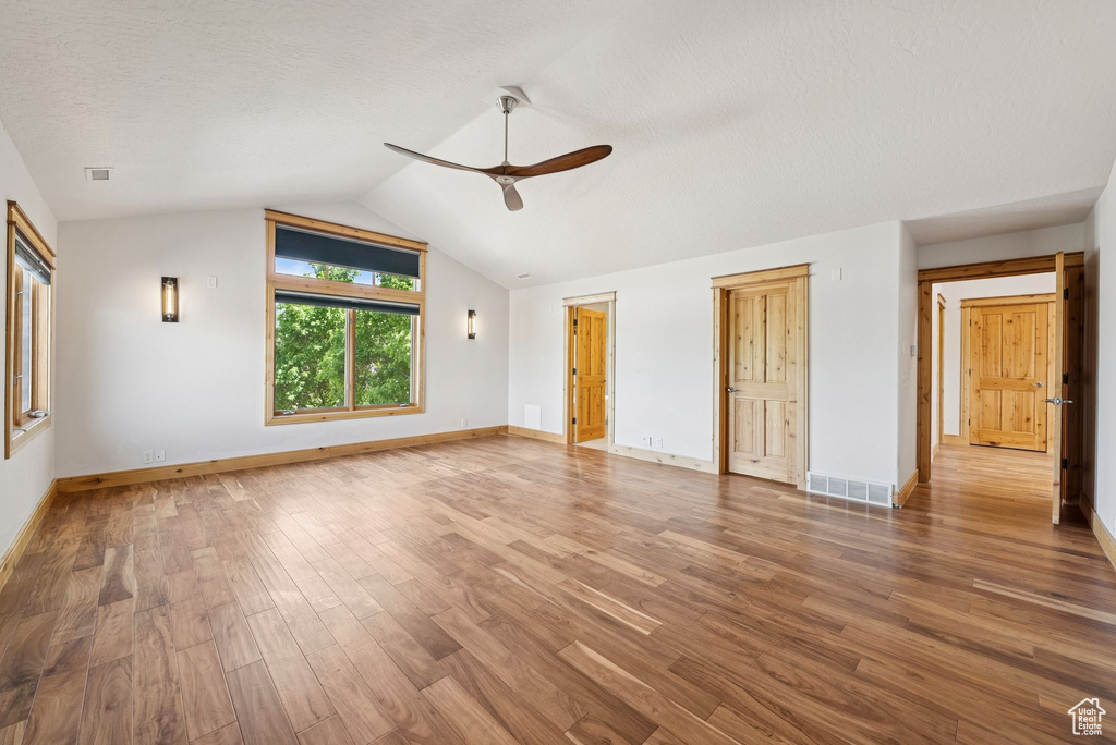 Unfurnished living room featuring a ceiling fan, lofted ceiling, and wood finished floors